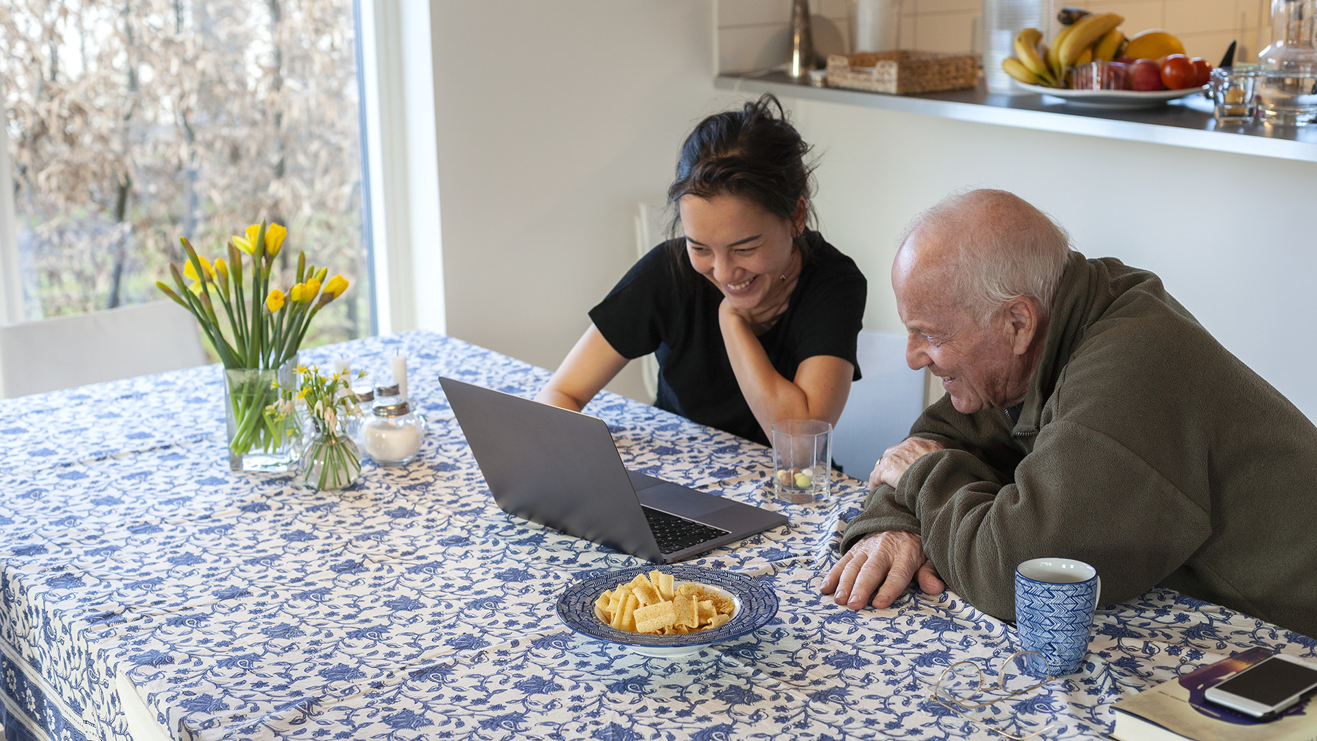 Young woman with grandfather using laptop