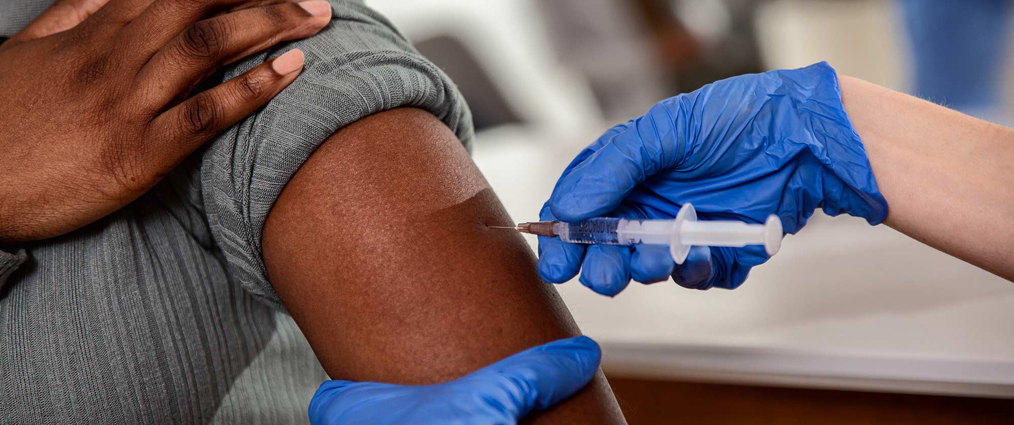 Close up of nurse hands giving vaccine to patient in clinic.