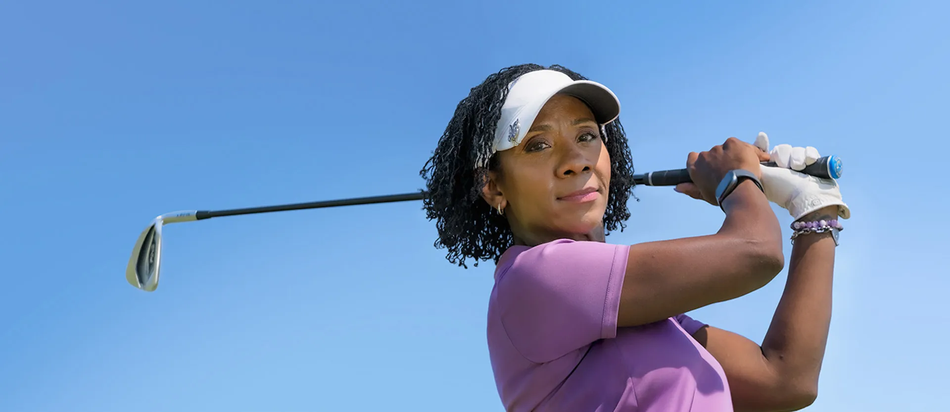 Toni swinging a golf club against a blue sky